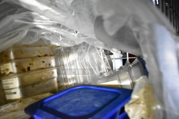 Interior of a mobile kitchen trailer showing plastic containers and storage bins amidst clutter, highlighting storage capacity.