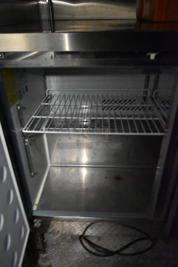 Interior of an Arctic Air cooler with a wire rack shelf and visible power cord. Clean stainless steel finish.