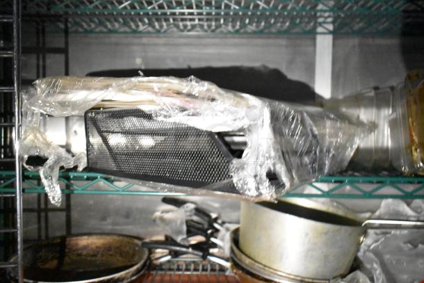 Mobile kitchen trailer image showing metal shelving with cookware and wrapped equipment. Features CaptiveAire hood, Pitco fryers, Arctic Air units.