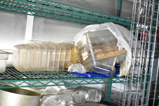 Mobile kitchen trailer interior with metal shelves holding plastic containers, cookware, and utensils.