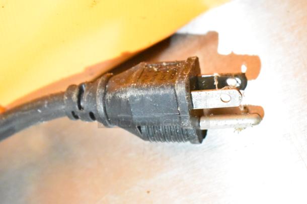 Close-up of a black power plug against a metal surface, highlighting electrical connection detail.