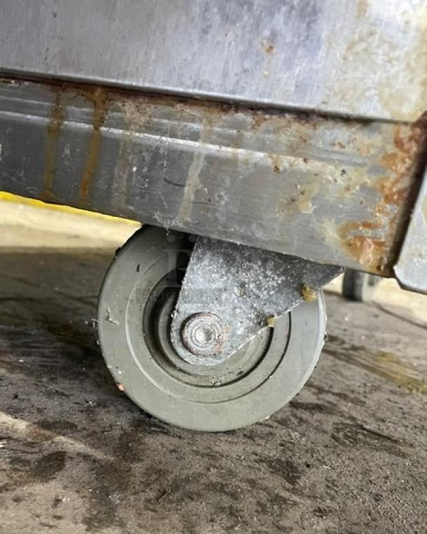 Old Hickory N7GRH rotisserie oven close-up on caster, showing wear and rust on stainless steel exterior.