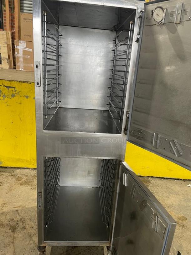 Alto-Shaam 1000UP dual compartment heated cabinet, stainless steel, on casters, open doors showing interior racks, model/serial visible.