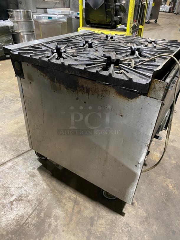 Montague commercial stainless steel 6-burner gas range and convection oven combo on casters, showing signs of use.