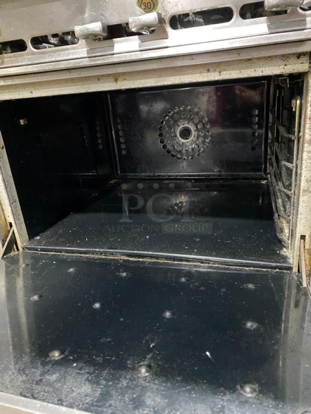 Montague commercial stainless steel gas-powered 6-burner range and convection oven combo on casters, interior view.