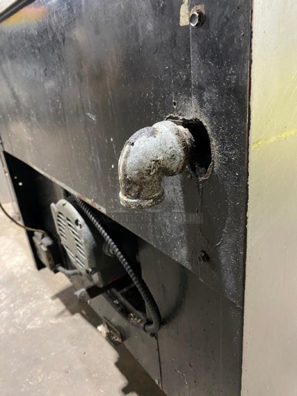 Montague commercial stainless steel 6-burner gas range with convection oven, on casters. Visible wear, rear view with pipe fitting.