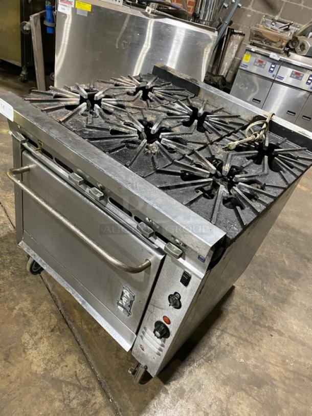 Montague stainless steel gas-powered 6-burner range with convection oven, on casters. Used condition, features durable build.
