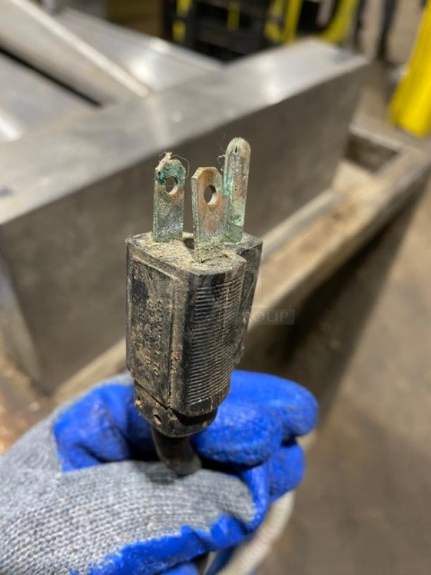 Alt text: Worn electrical plug with corrosion held by a gloved hand.