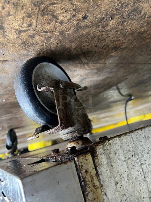 Patriot commercial oven caster, metal and rubber, attached to stainless steel base. Model FMCOF54NG, visible rust.