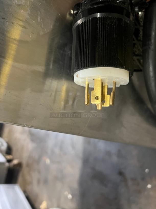 Power plug of Electro Freeze Freedom 360 soft serve machine model 78RMT232. Gold prongs, black and white casing, attached to stainless steel surface.