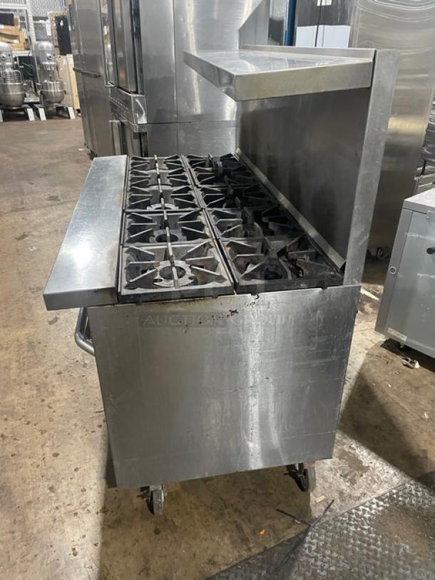 American Range commercial stainless steel gas-powered 6-burner with flat griddle, double oven, broiler, backsplash, on legs.