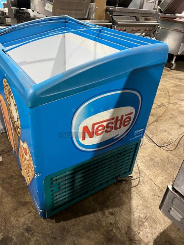 AHT Reach Down Freezer Merchandiser, Model RIO S100, Serial 60060100000925. Features Nestlé branding, 120V, 1 Phase. Visible wear.