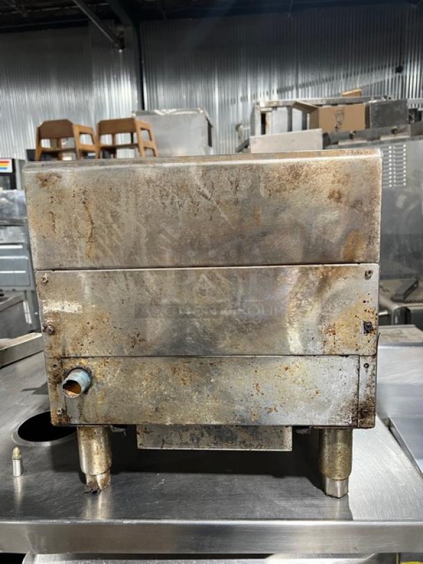 CPG natural gas 15-inch countertop charbroiler grill on legs. Rusty exterior indicative of used condition. Industrial setting.