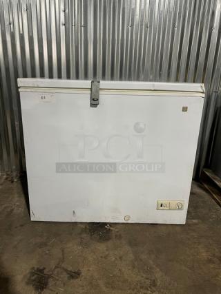 GE white deep chest freezer, model FCM7SUBWW, serial GS101196, 115V 1 Phase. Visible surface wear. Power controls on front.