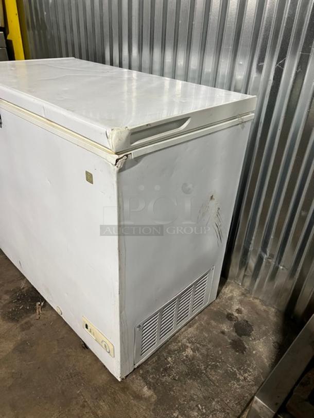 GE white deep chest freezer, model FCM7SUBWW, showing wear and dents. Serial GS101196 visible. 115V, 1 phase.