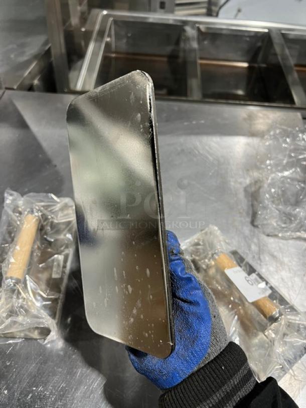 Brand new Vollrath stainless steel weight, rectangular, shiny finish, packaged with wooden handles visible in sealed bags.