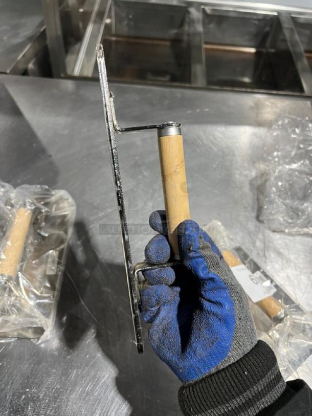 Brand new Vollrath stainless steel weight with wooden handle, shown in worker's gloved hand, pristine condition.