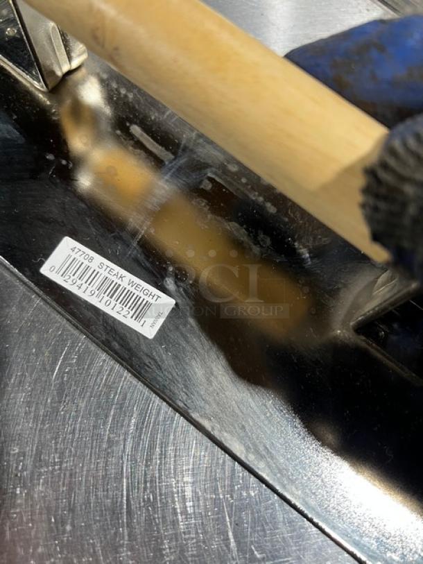 Brand new Vollrath stainless steel steak weight with wooden handle. Visible label reads "47708 STEAK WEIGHT."