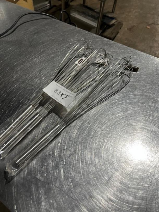Set of three new Winware FN20 hand held whisks, in package, stainless steel, perfect condition, placed on a metallic surface.