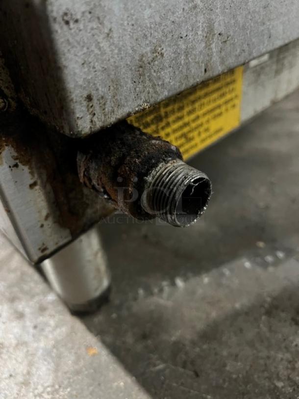 Starmax natural gas 24" flat griddle, visible wear, on legs. Label indicates model and safety instructions. Thermostatic controlled.