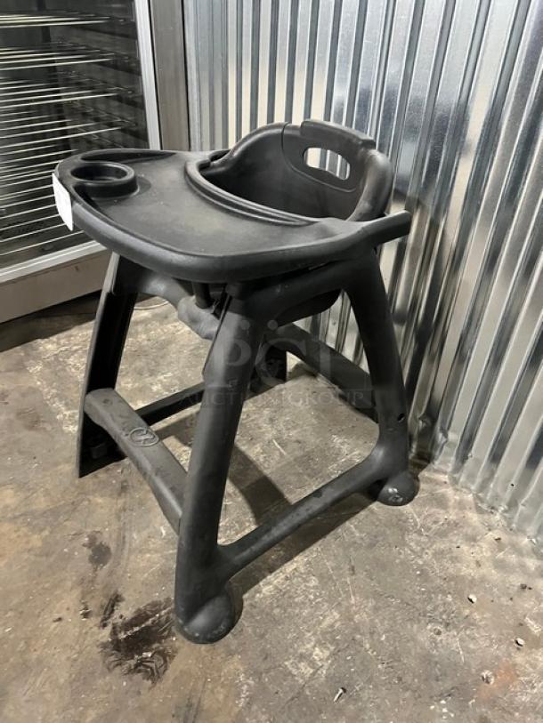 Commercial black restaurant high chair with tray, sturdy plastic, integrated cup holder, well-used condition.
