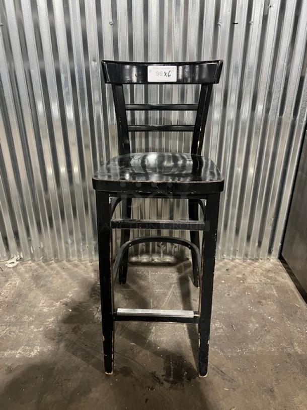 Black bar-height chair, commercial grade, wooden slatted back, used condition with visible wear. Label reads "96 X6."
