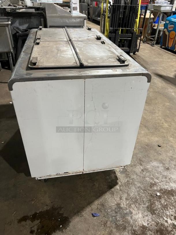 Kelvinator white ice cream dipping cabinet with flip-top lid, on casters. Visible wear; suitable for commercial use.