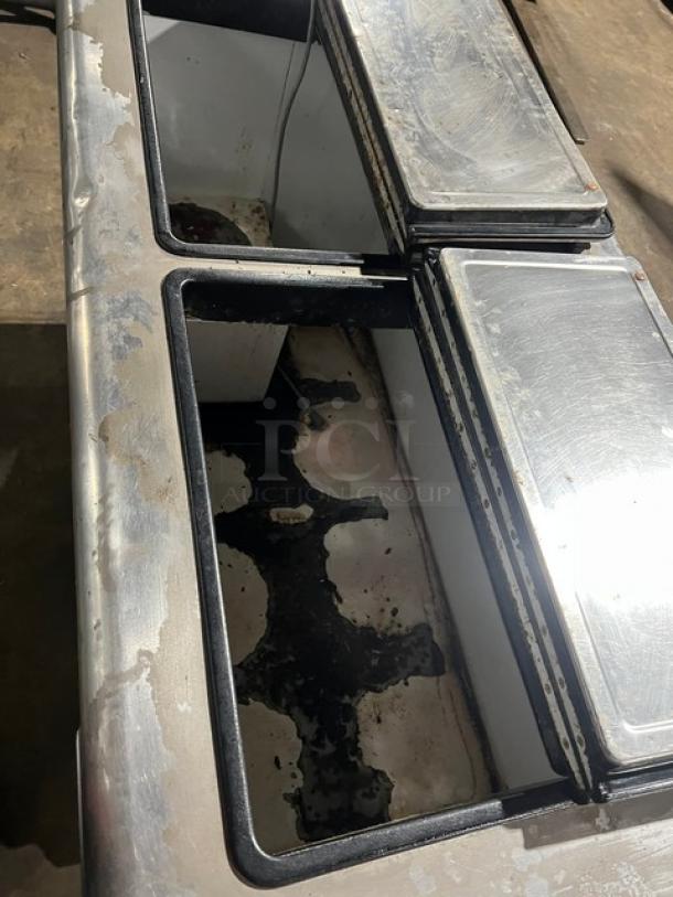 Kelvinator white ice cream dipping cabinet with flip-top lid on casters, visible wear and rust on interior surfaces.