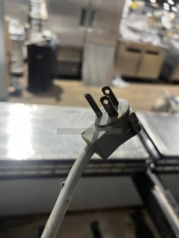 Kelvinator Commercial white ice cream dipping cabinet with flip-top lid and casters, power plug visible.