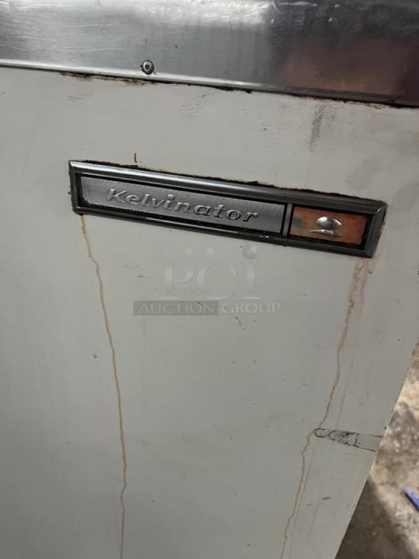 Kelvinator commercial white ice cream dipping cabinet with flip-top lid, on casters. Visible brand label. Some wear.