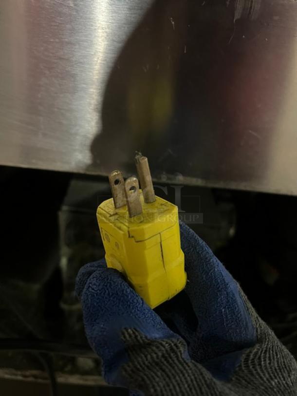 Yellow plug for Leader Commercial 115V 1 Phase refrigerated bakery display case, glove and metal surface visible.
