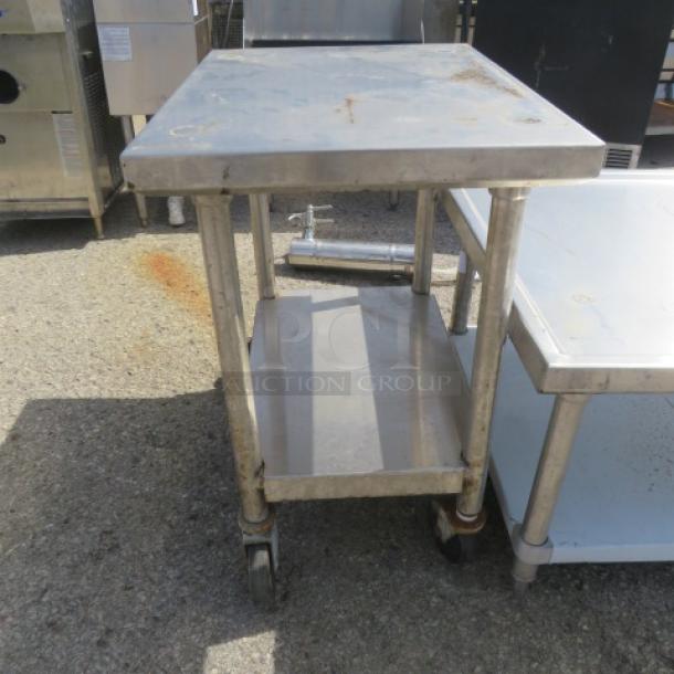 Stainless steel table with undershelf, 28x20x30, on casters, used condition, ideal for kitchen or commercial use.