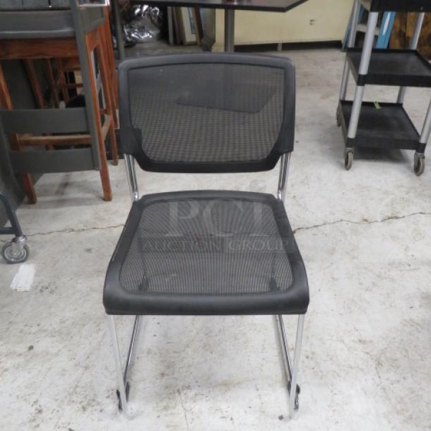 Stackable metal and black poly event chair with mesh seat and back, chrome legs, suitable for events, good condition.