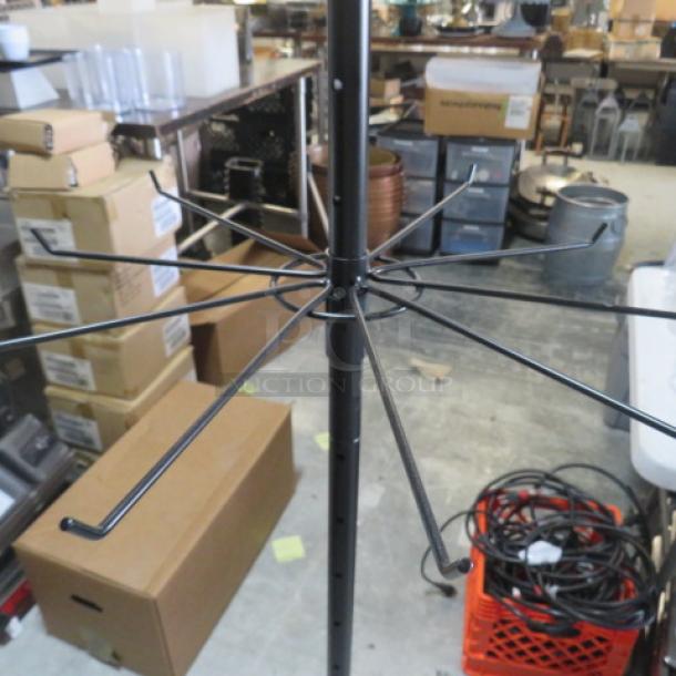 Metal display rack on casters with multiple hooks, ideal for retail. Black finish, adjustable height. Used condition.