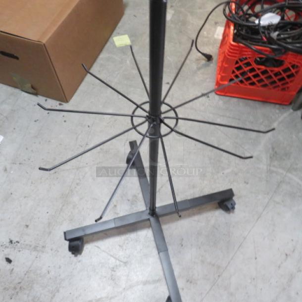 Metal display rack on casters, black finish, sturdy construction, multiple arm hooks for hanging items, good condition.
