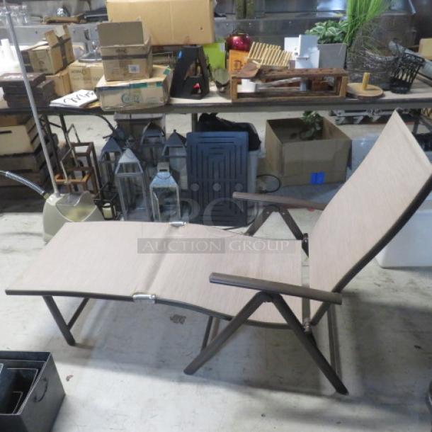 Foldable lounge chair with wooden armrests and beige fabric seat, shown in a storage area. Excellent condition, sturdy frame.