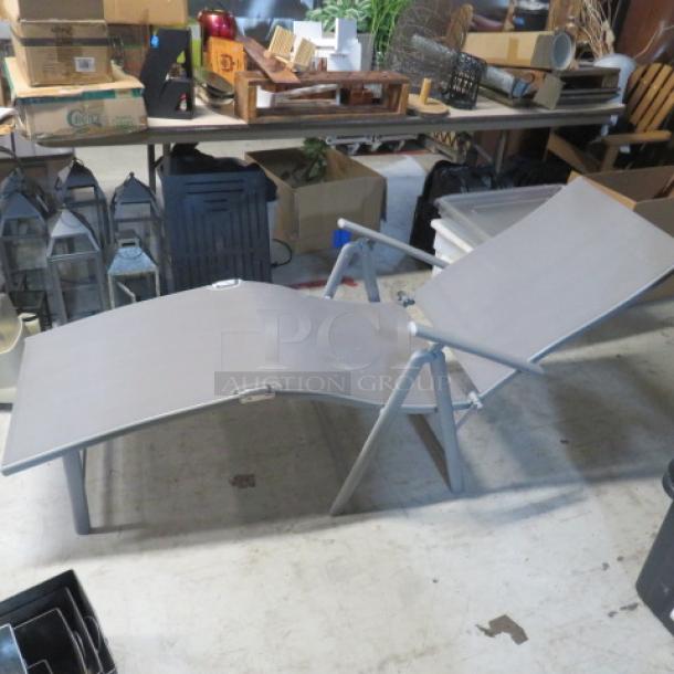 Foldable lounge chair, gray fabric, metal frame, adjustable backrest, used condition, suitable for outdoor use.