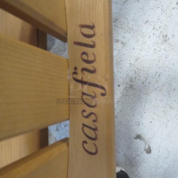 Casa Fiela kid-sized wooden Adirondack chair, natural finish, sturdy construction, engraved branding visible on the slat.