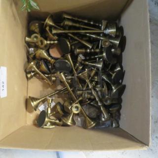 Assorted brass candlesticks in a cardboard box, various sizes and styles, in good condition. Auction lot number 142 visible.