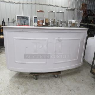 One white wooden curved portable bar with under storage. Dimensions: 77x30x42 inches. Includes panel detailing.