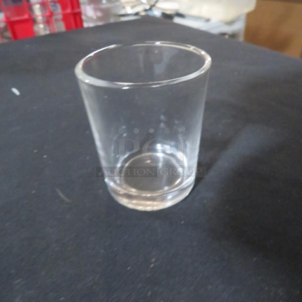 New Acopa 2.5oz shot glass on dark surface, in pristine condition. Clear glass with smooth finish.