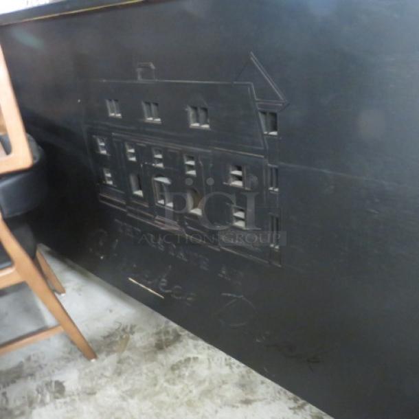 Portable bar with black laminate serving shelf, featuring two stainless steel ice wells, bottle rails, and storage, on casters.