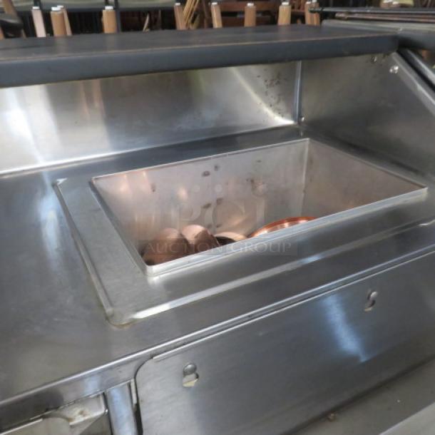 Portable bar with two stainless steel ice wells, bottle rails, black laminate serving shelf, on casters. Size: 95x31x46 inches.