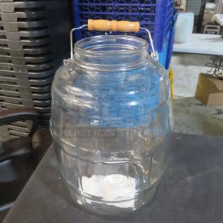 Glass barrel jar with handle, no lid; clear glass with ribbed design; wooden handle; used condition.