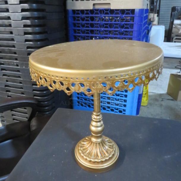 A 10-inch gold cake stand with ornate lace-like trim, standing on a decorative pedestal base, in good condition.