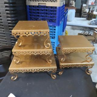 Assorted gold stands with ornate edges and spiral legs, featuring three stacked sizes. Used condition.