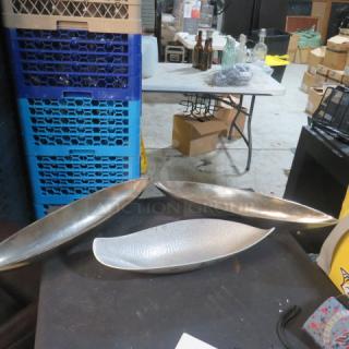Assorted metal serving trays, oval-shaped, set of three. Silver-toned with textured finish. Used condition.