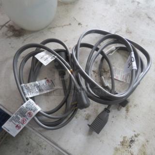 Gray electrical cords, 250 Volt, 9A, 20AMP, with attached warning labels and two-prong plugs, coiled on a tabletop.
