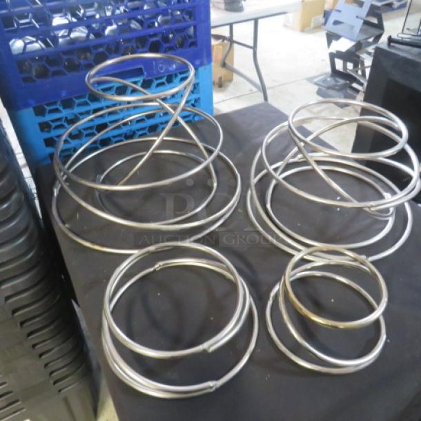 Stainless steel riser/holders in assorted sizes. Multiple interlocking rings. Likely used for display purposes.
