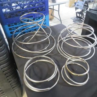 Stainless steel riser/holders in assorted sizes. Multiple interlocking rings. Likely used for display purposes.